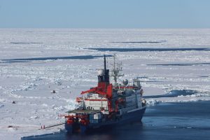 Polarstern liegt während der Driftstation an einer Scholle. Auf der Backbordseite markieren verschiedene Installationen und Flaggen die unterschiedlichen Messpunkte auf und unter dem Meereis. Foto: Svenja Kohnemann.